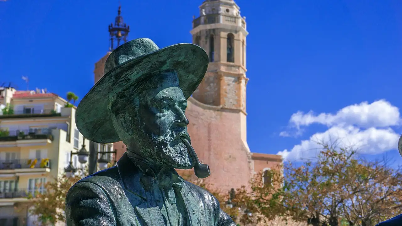 A bronze statue and the church tower in the old town of Sitges
