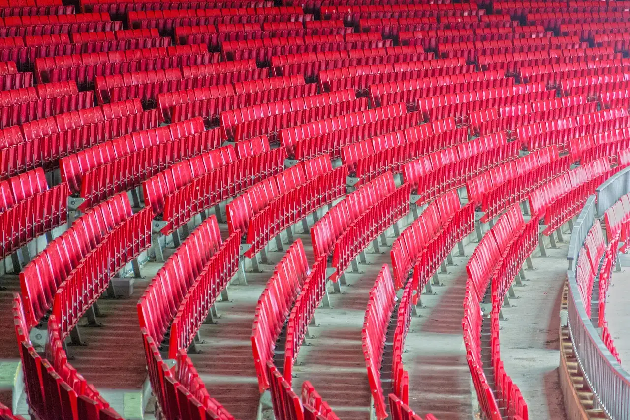 Curved rows of empty red seats in a large football stadium