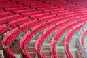 Curved rows of empty red seats in a large football stadium