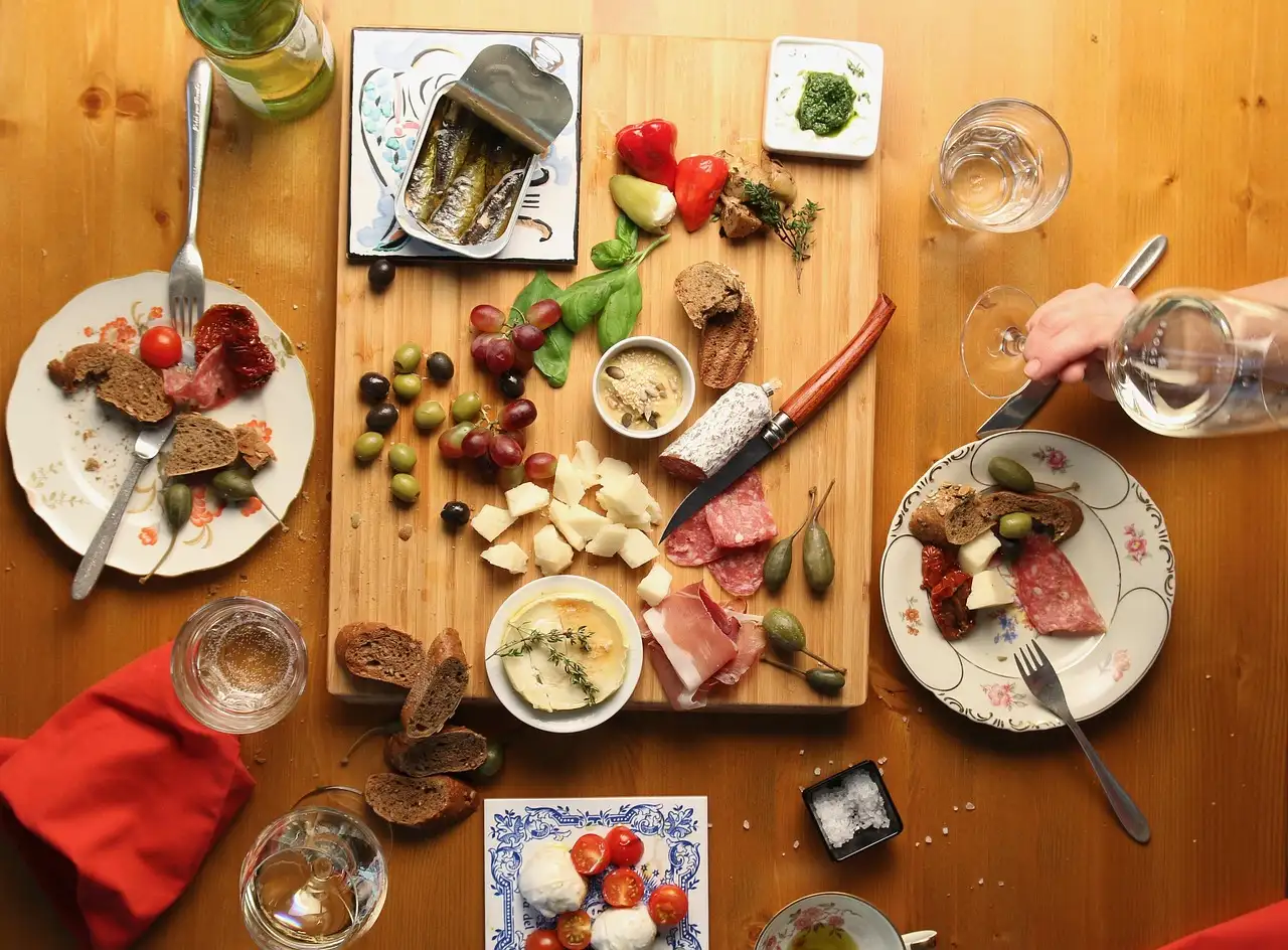 Table spread with a board of cured meats, cheese, olives, bread and small plates