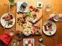 Table spread with a board of cured meats, cheese, olives, bread and small plates