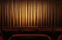 Lit stage curtain above rows of red theater seats