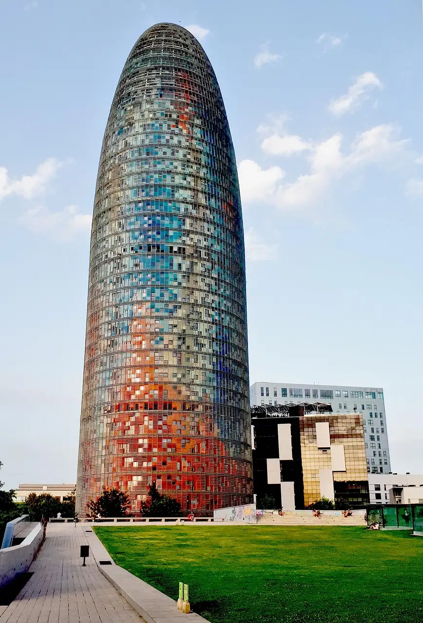 Torre Glòries, the rounded glass tower with the observation deck at its top, above a lawn