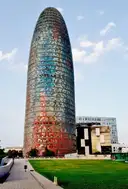 Torre Glòries, the rounded glass tower with the observation deck at its top, above a lawn