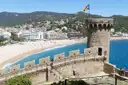 The old walls and round tower of Tossa de Mar above a curved sandy beach