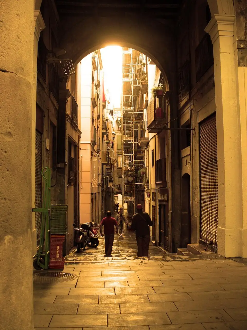 A stone archway in the Gothic Quarter opening onto a lane in golden light