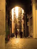 A stone archway in the Gothic Quarter opening onto a lane in golden light
