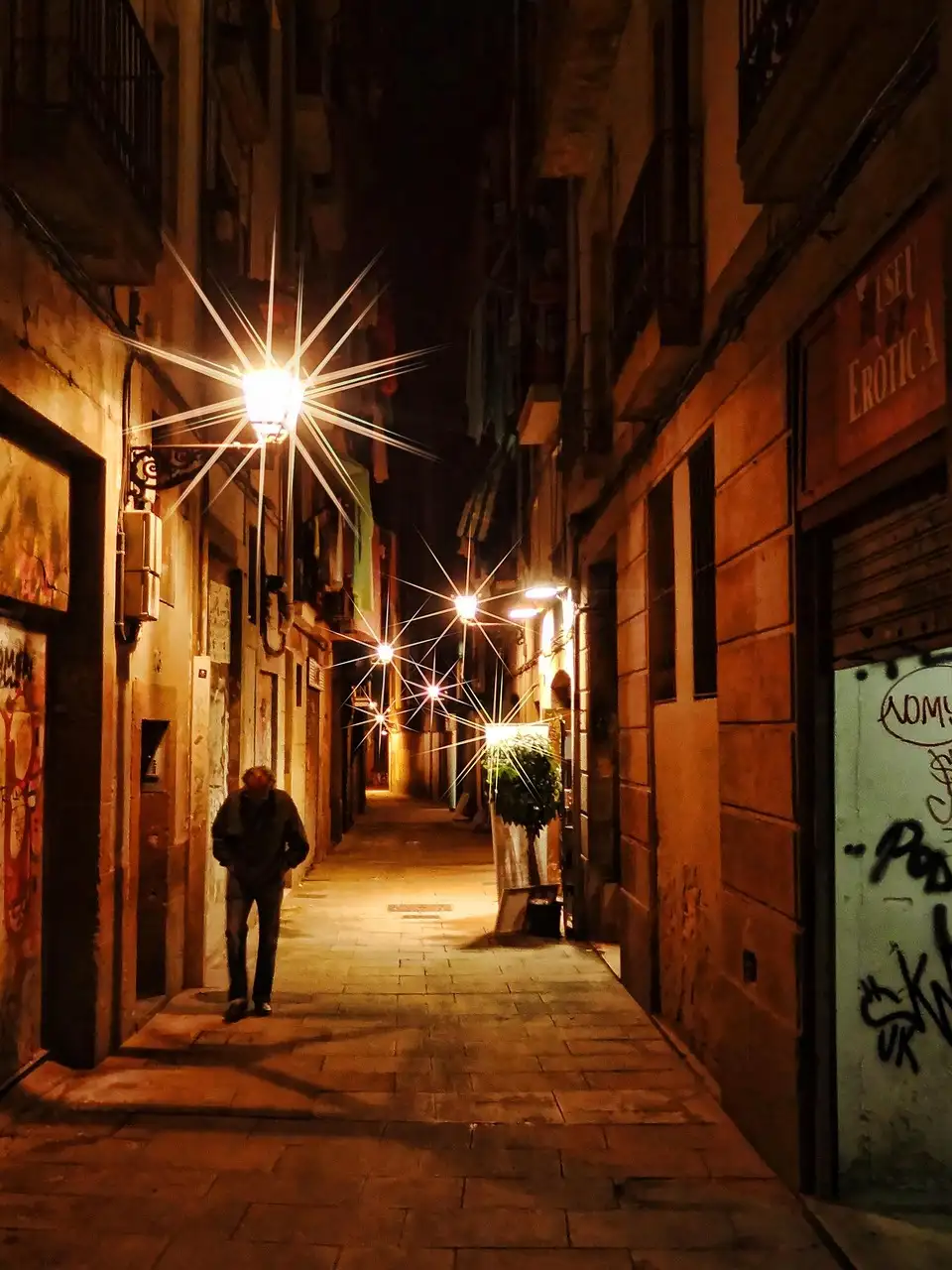 A narrow old-town lane at night, lit by wall lamps