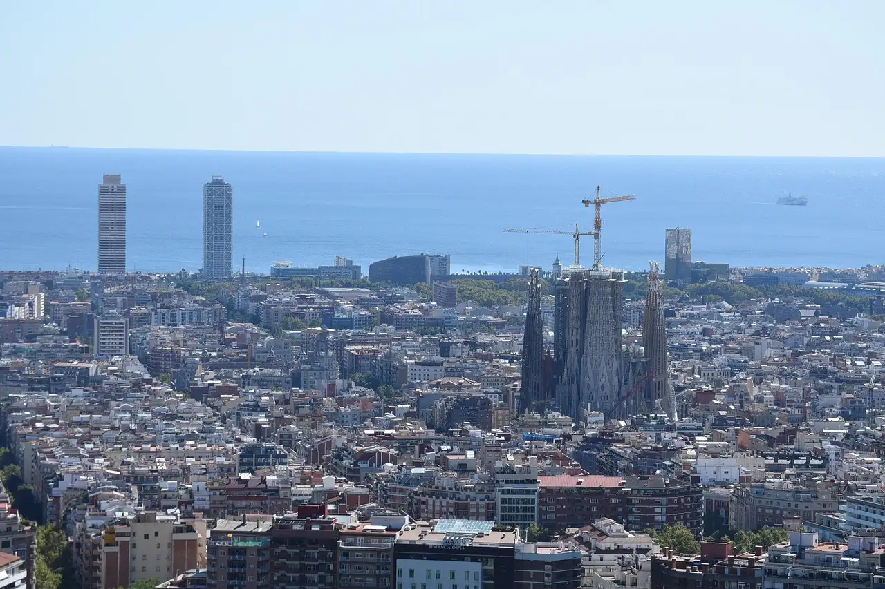 Barcelona's rooftops from a hill, with the Sagrada Família, two seafront towers and the sea behind