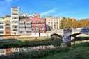 Colorful houses on the Onyar River in Girona, next to a stone bridge