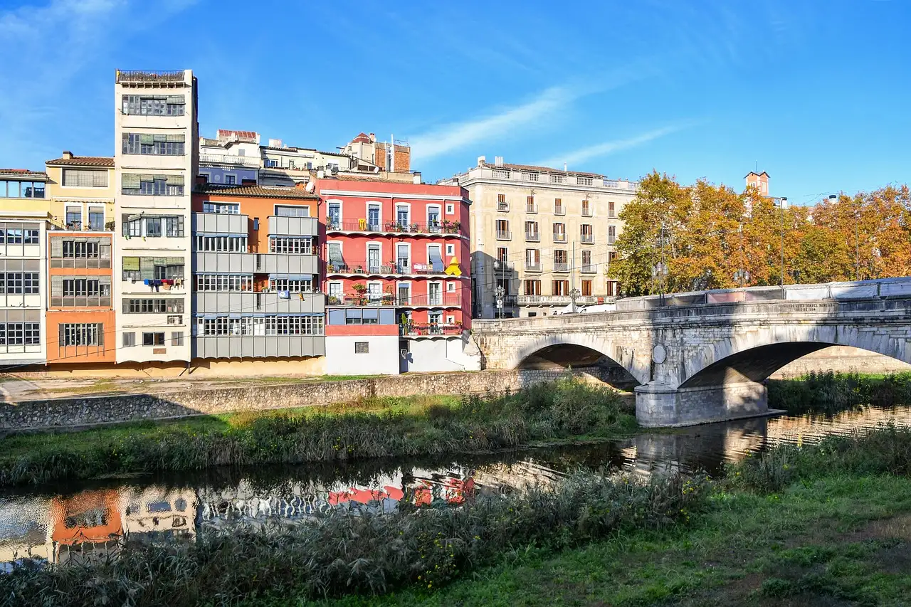 Colorful houses on the Onyar River in Girona, next to a stone bridge