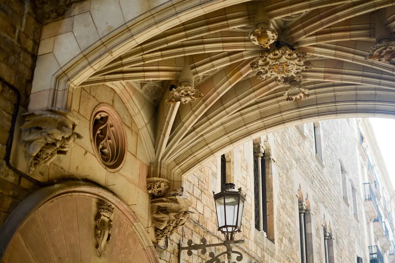A carved stone arch and an iron street lamp in a narrow lane of Barcelona's old town