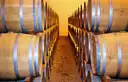 Two long rows of oak wine barrels in a cellar, lit warm at the far end